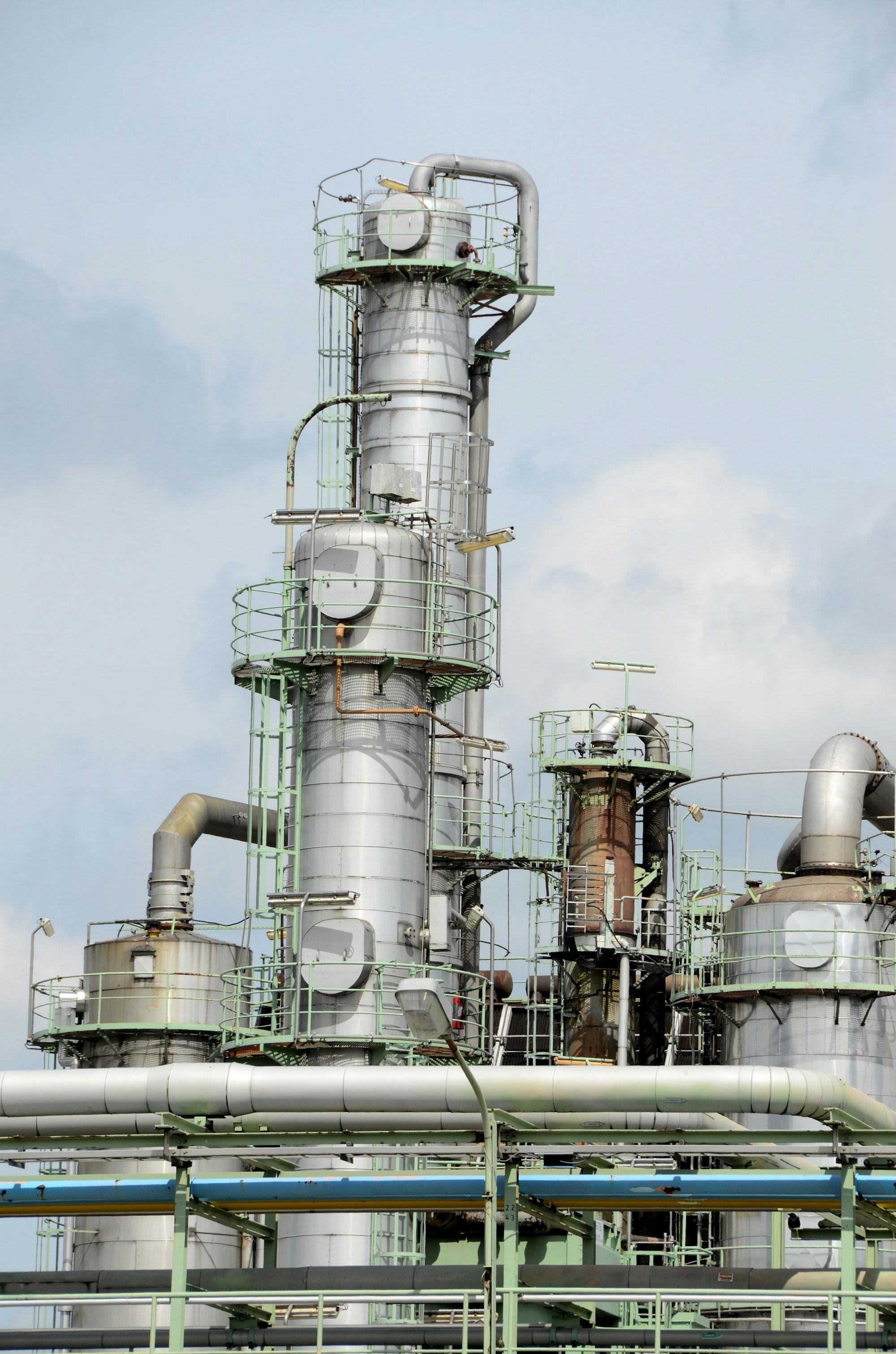 Steel process columns, platforms and pipework against a pale sky